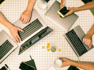 Top view of a team collaborating with laptops, phones, and notes in a modern office.